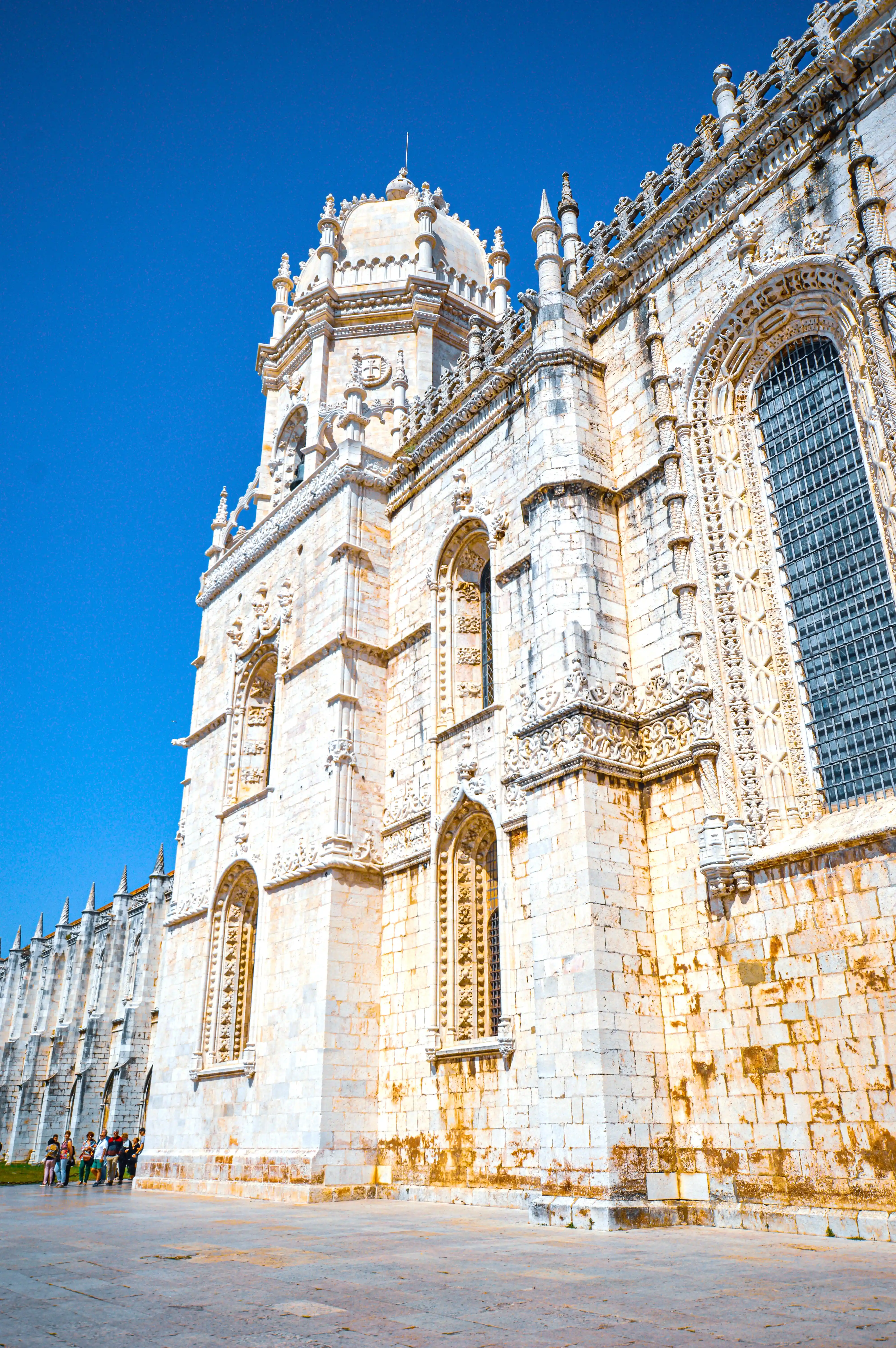 The Jerónimos Monastery, a UNESCO World Heritage site in Lisbon, Portugal, with detailed Manueline architecture and a bright blue sky.